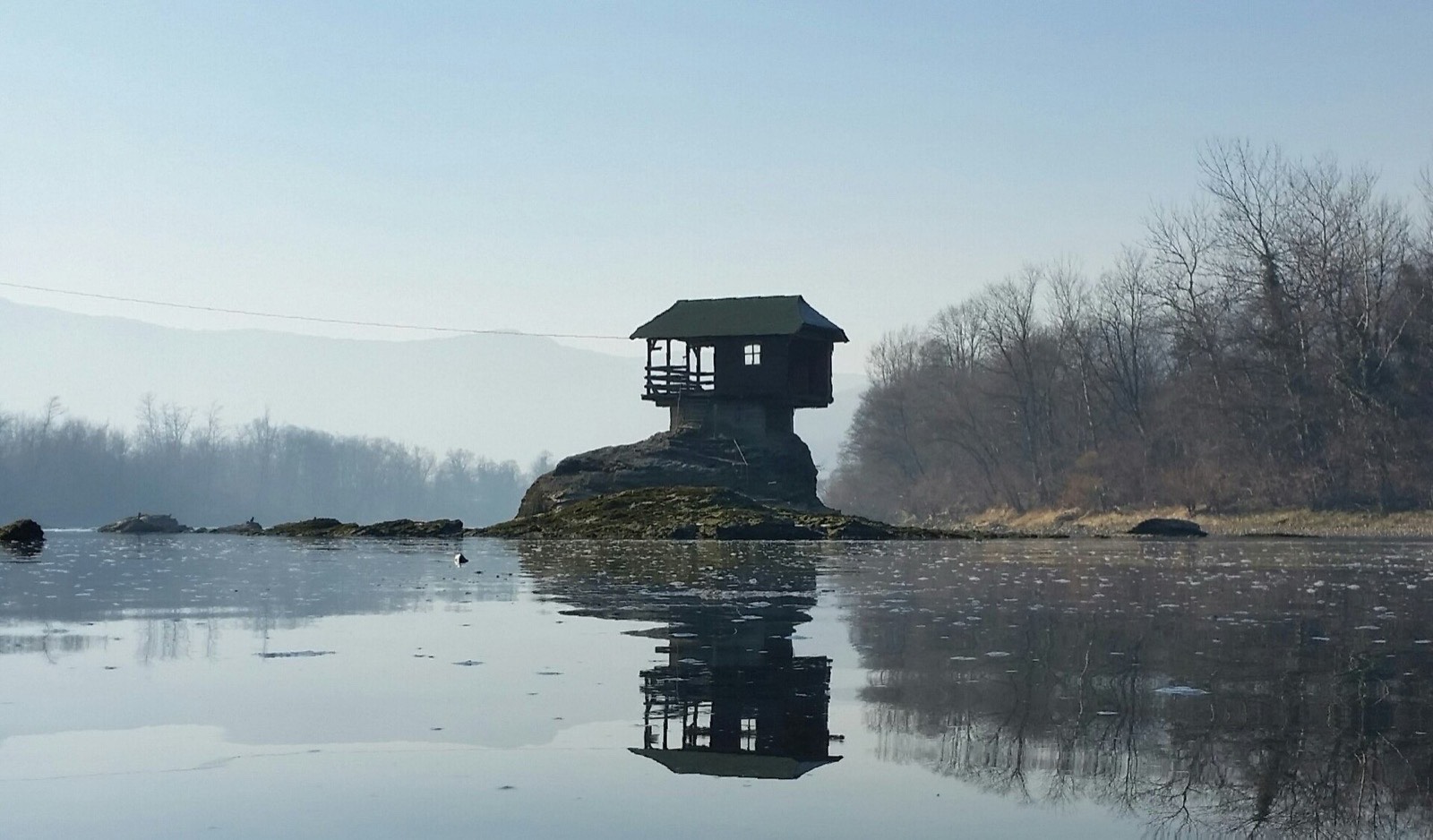 Tiny wooden house on a rock in the middle of the river